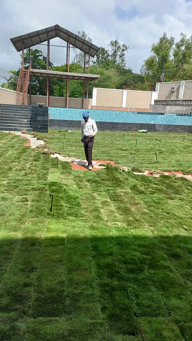 Person tending the lawn with a covered structure in the background